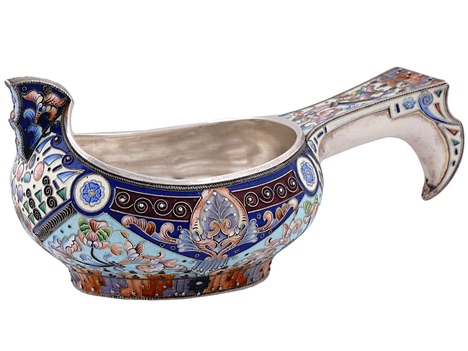 A RUSSIAN SILVER AND ENAMEL KOVSH, 20TH ARTEL, MOSCOW, 1908-17: 20th Artel, Moscow, 1908-1917.Of a traditional form, with a raised prow and shaped hook handle, the exterior is adorned with shaded cloisonne enamel Neo-Russian floral patterns in shades of blue, gree