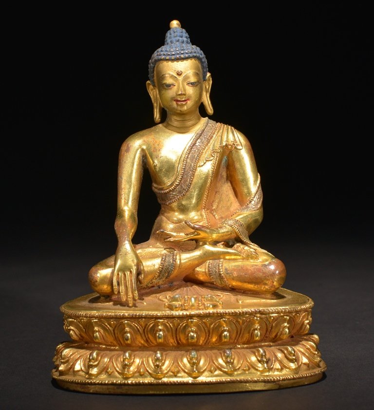 A GILT-BRONZE FIGURE OF BUDDHA: The bronze figure is seated in a double lotus base in dhyanasana. Wearing a traditional robe and head in dark brown color. There is a double vajra design on the base. 5 1/4 in. (13.3 cm) tall. 16th Ce
