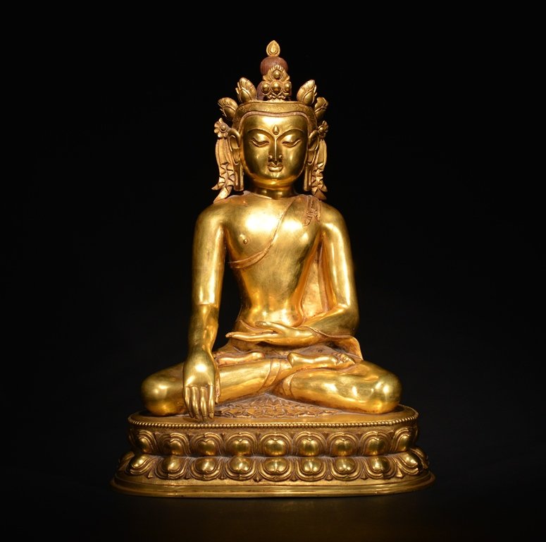 A GILT-BRONZE FIGURE OF BUDDHA: Seated in dhyanasana on a double lotus base with beaded rims, his hands in bhumisparsamudra and dhyanamudra, wearing a long flowing robe over is left shoulder, his face with serene expression, downcas