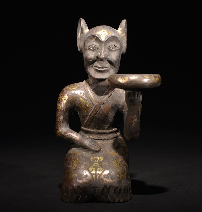 A GILT-BRONZE FIGURE: The figure is kneeling and holding a large plate on his left hand and the exterior is decorate with numerous imperial designs. 6 9/16 in. (16.6 cm) tall. Han Dynasty