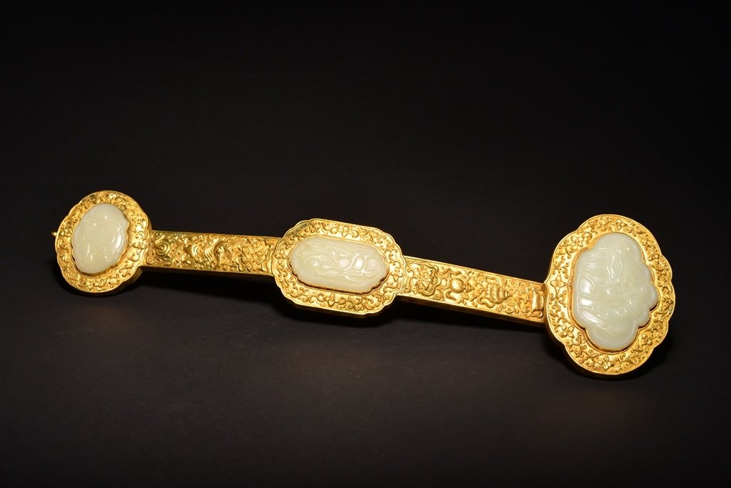 A WHITE JADE INLAID GILT-BRONZE RUYI SCEPTER: The scepter is overall a gilt golden color and decorate with three pieces of jade. 21 9/16 in. (54.5 cm) long. Qing Dynasty