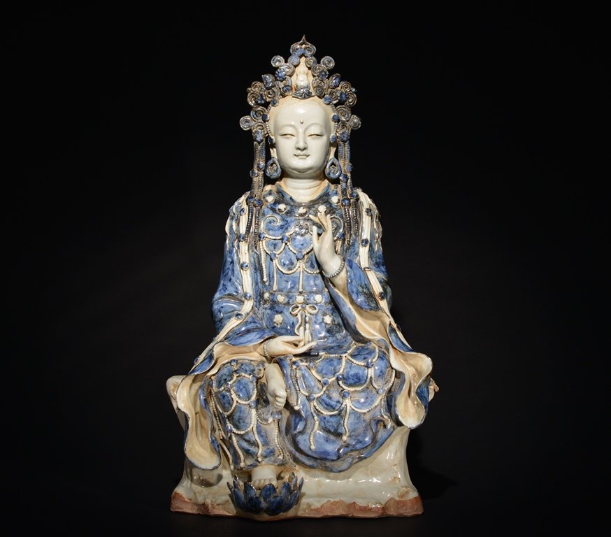 A LARGE BLUE AND WHITE FIGURE OF GUANYIN: The seated figure is of a Guanyin wearing traditional robes and crown and decorated with imperial designs. 21 in. (53.4 cm) tall. Ming Dynasty