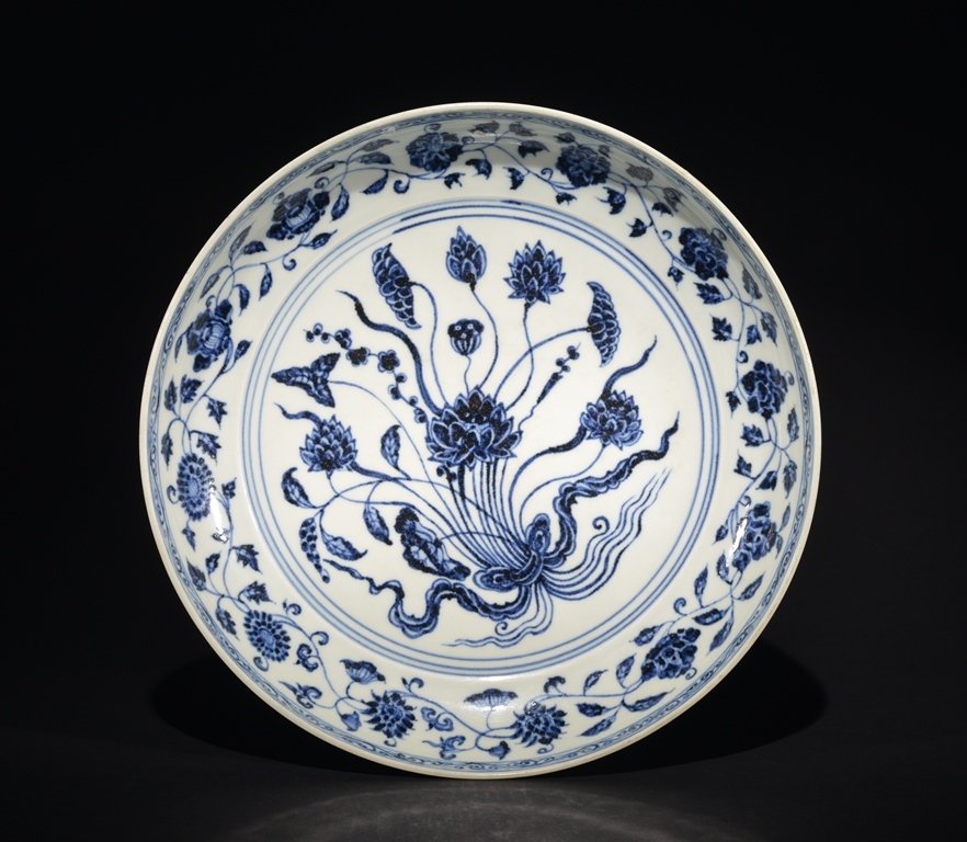 A BLUE AND WHITE LOTUS DISH: The dish is concave-shaped and the exterior is decorated with numerous flower blossoms. 12 3/4 in. (32.4 cm) diameter, 2 1/2 in. (6.4 cm) tall. Ming Dynasty
