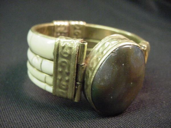 NAGA SHELL BRACELET WITH AGATE AND GOLD PLATE: Naga shell bracelet with agate and gold plate decoration. The agate cabachon measures 34mm x 28mm. The band is 1" wide. The lock works fine. The bracelet measures 2.75" in diameter. It weighs 0.25lb.