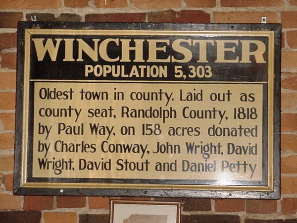 WINCHESTER population 5,303 metal sign with wood f: WINCHESTER population 5,303 metal sign with wood frame,"Oldest town in county.Laid out as county seat,Randolph County,1818 by Paul Way,on 158 acres donated by Charles Conway,John Wright,David Wright,M