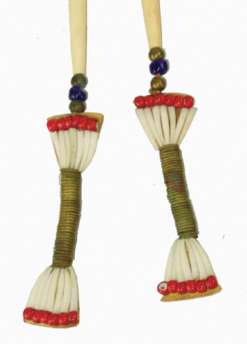 Plains Hair Drops: Mid 1900s, Unique set of brass wire wound hair pieces made with dentalium and whiteheart tradebeads on rawhide, all suspended from 4" bone hairpipes. Very good condition. 20" long each