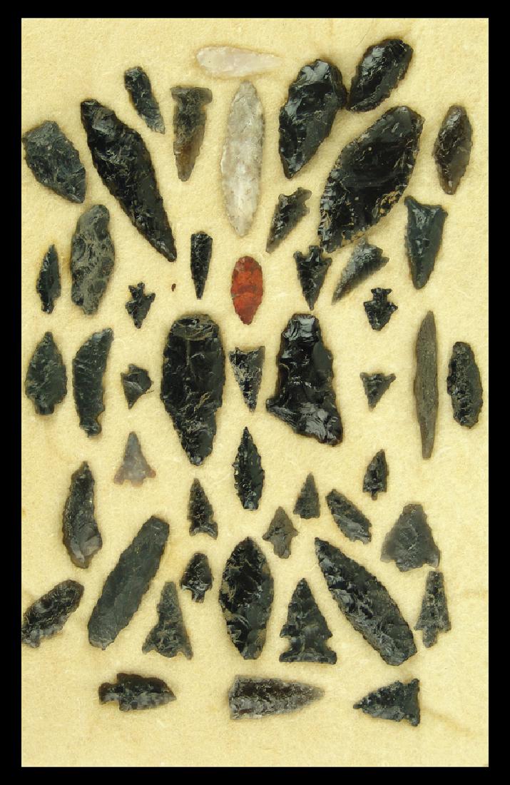 Obsidian Points and Tools: Collection of approximately 48 whole and fragment bird points, blades, and tools, mostly obsidian, housed in a 12" x 8" ryker mount. Various conditions.Largest 2-3/4"Pre Historic