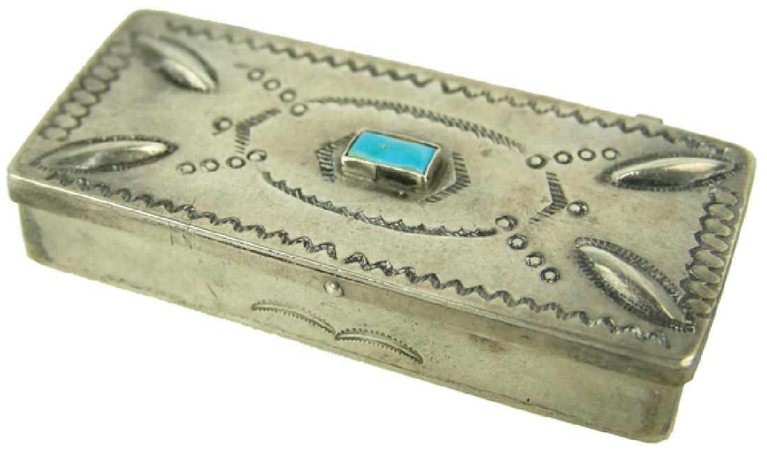 Navajo Silver Pill Box: Vintage, handwrought all silver hinged box with stamped designs, repoussé accents, two internal compartments, and a rectangular cut single turquoise stone. Very good condition.1/2" x 1" x 2-1/2"Mid 1
