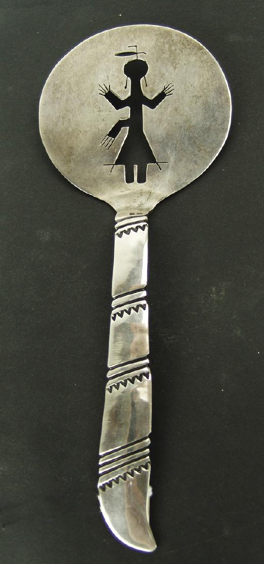 Navajo Silver Utensil: Heavier gauge handwrought all silver serving utensil with stamped handle and round body having female figure cut out. Very good condition.8"Ca. 1960s