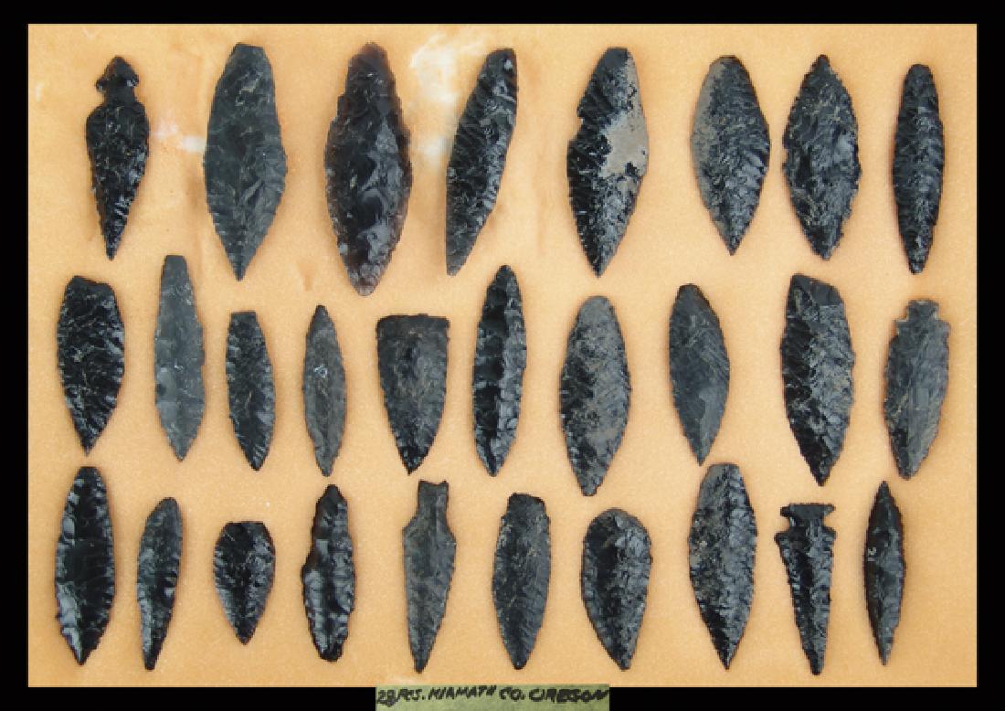 Oregon Obsidian Blades: Wonderful display of 28 large black obsidian blades and spears marked "28 pcs. Klamath Co. Oregon." All in good to very good condition. In 17" x 12" ryker mount.Largest 3-3/4"Pre Historic