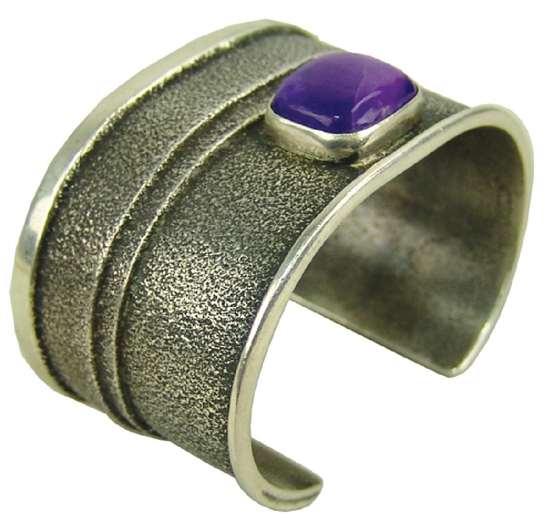 Navajo Bracelet: Outstanding, handwrought, all silver cuff bracelet cast in tufa stone with single, bright purple sugilite stone. Very good condition, unsigned.Late 1900s5" + 1" x 1-7/8"