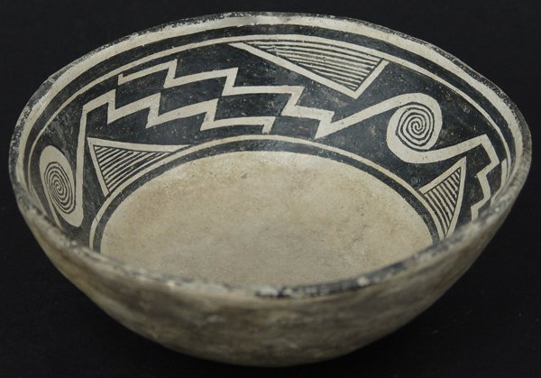 Mimbres Pottery Bowl: Fine, black-on-white bowl with 2" negative design band filled with interlocking scrolls, hachured triangles, and zigzag wide line elements. Very good condition, kill-hole filled in, some professional 