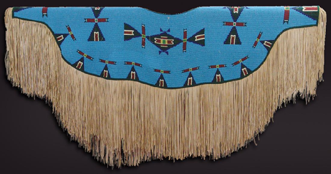 Plains Fully Beaded Yoke: Amazing, lazy stitch beaded ladies dress yoke with traditional symbols on a blue field, and with fine, extra-long fringe. Beaded on the front and back.Ca.1980s18" x 54" + fringe