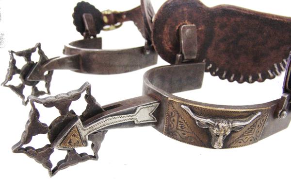 L & M Western Spurs: Early/mid 1900s AdultGreat, single mounted spurs with arrow shanks, the heel bands with steer heads on brass plaques, with Leddy Foster Leathers, and unique 2" rowels made up of six, joined steer head