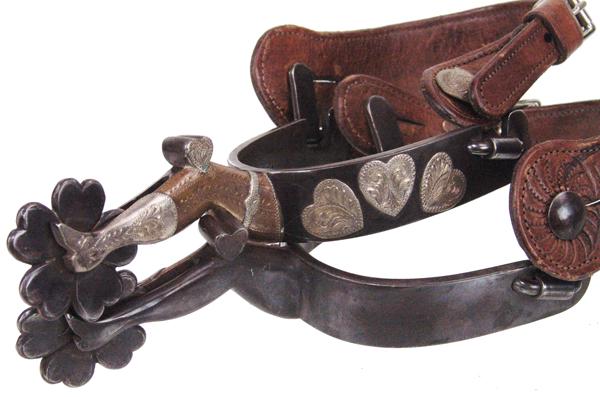 Jerry Galloway Gal Leg Spurs: Mid 1900s AdultWonderful pair of single mounted spurs with gal leg shanks, the bands decorated with hearts, with silver mounted hanging heart buttons, and with special rowels made from hearts. Marked 