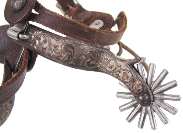Les Vogt Spurs: Mid 1900s Adult Full, single mounted and engraved commercial western spurs with cast metal rowels, and oak leaf leathers. Very good condition.
