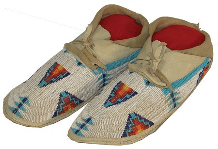 Southern Plains Beaded Moccasins: Beautiful pair of extra long lazy stitch beaded moccasins with asymmetrical geometric designs on a white field. Very good condition, commercial buckskin with hard soles. Circa:Mid 1900s Size:12-1/2" l