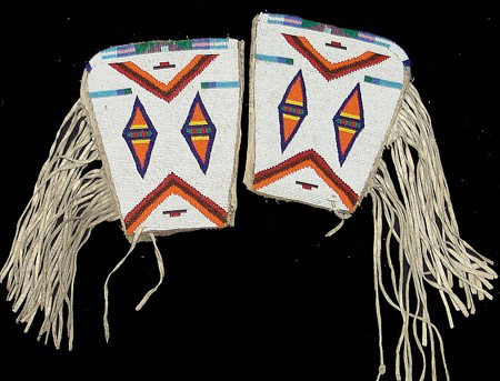 Crow Beaded Cuffs: Circa Mid 1900s, Beautiful fully beaded buckskin cuffs with fringed edging and colorful geometric symbols on a white field. Very good condition. 8" x 6" each