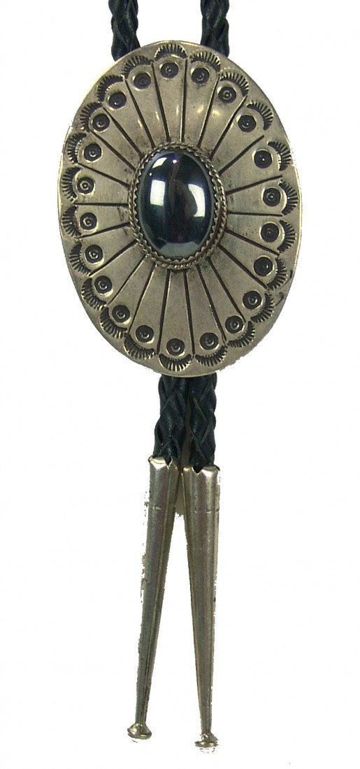 Navajo Bolo Tie: Traditional oval shaped stamped silver bolo tie set with a beautiful single hematite stone. Very good condition, with Turpin Pawn ticket. Circa: Late 1900s Size: 1-1/2" x 2"