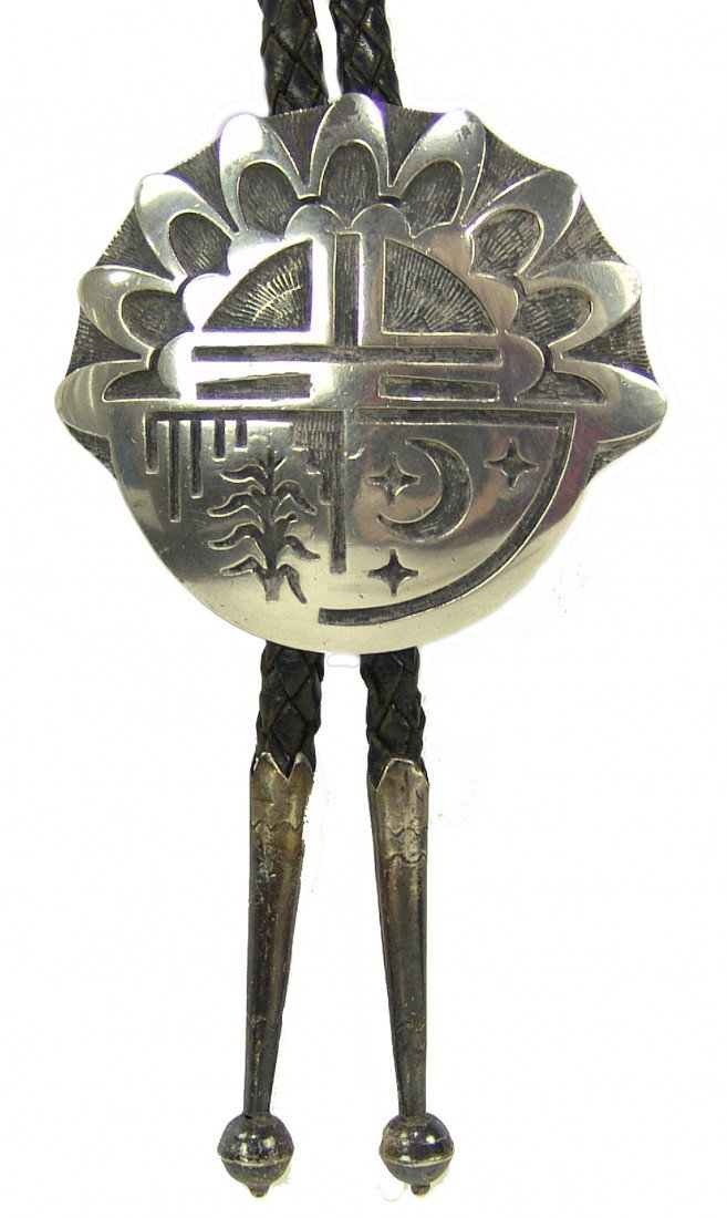 Hopi Bolo Tie - Glenn Lucas: Fine silver overlay bolo with "Tawa kachina rising behind rain & corn; stars & crescent moon at right". Very good condition. Ex: Dockstader collection (with provenance). Circa: 1960s Size: 2-1/2" x 2-