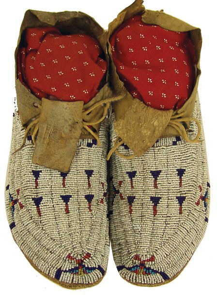 Sioux Beaded Moccasins: Early 1900s, Very fine pair of sinew sewn and lazy stitch beaded elk hide moccasins with hard buffalo rawhide soles and interesting arrow designs on a full white field, these are beaded using tiny 22-