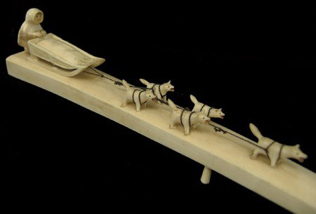 Eskimo Ivory Carving: Mid 1900s, Very fine well carved vintage ivory sled-dog scene done on a tusk, including five dogs, a sled, and Eskimo driver. All in very good condition, with scrimshaw features. 1-1/2" x 14"
