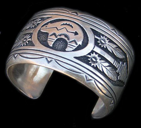 Navajo Bracelet - Tommy Singer: 1980s, Heavy weight fine Navajo sterling silver cuff bracelet with heartline bear, feathers, and other stamping. Signed. 7-1/2" + 1-1/2" x 1-3/4"