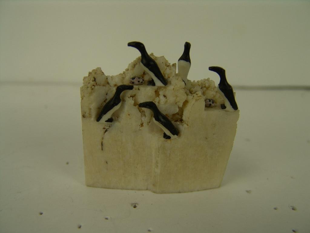 Ivory Sculpture: Eskimo ivory sculpture of 5 penguins(?); 2 with eggs, on a cliff face. Size: 2" x 1-1/2"