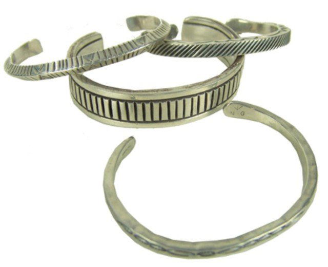 4 Silver Bracelets: Four beautiful hand-stamped solid silver bracelets, the largest one signed "KRS," the others "JT," "Kee Nataani," and "NG." All in very good condition. Circa: Late 1900s Size: 5-5/8" + 1-1/2" x 5/8" l