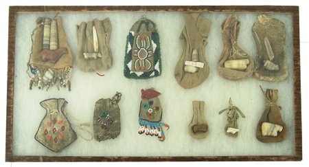 Beaded Bag Collection: Various ages, Collection of 11 miscellaneous small beaded fetish bags including: Plateau, Plains, Woodlands; six of the Plains bags have stone fetishes - in 22" x 12" display case. Largest 6" x 3"