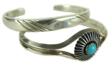 2 Navajo Bracelets - Joe H. Quintana: Ca. 1985, Pair of fine hand wrought all-silver bracelets, one with a single turquoise stone in a beautiful rosette setting. Very good condition. Ex. Irma Bailey Collection. 5-1/2" + 1" x 1/4", 4-3/4" 