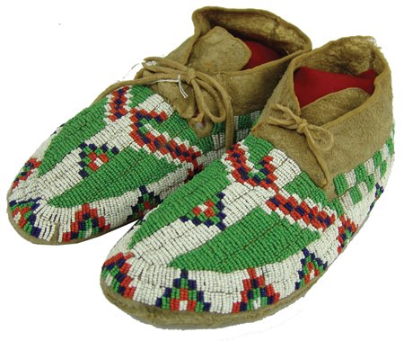 Sioux Beaded Moccasins: Early 1900s, Classic pair of sinew sewn and lazy stitch beaded buffalo hide moccasins with striking geometric pattern and hard rawhide soles. Very good condition. 11"