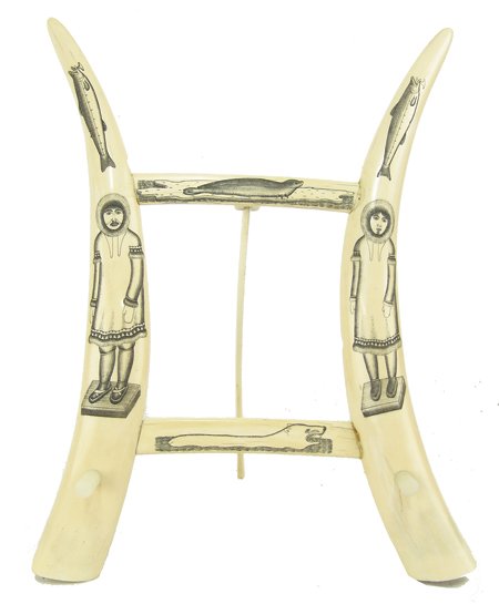 Eskimo Ivory Book/Picture Holder: Mid 1900s, Intricately etched ivory tusks with ink scrimshaw depicting a male and female in full dress, sturgeon, a polar bear, and a seal; made into a table display. Good condition, minor repairs, on