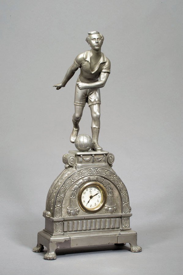 A spelter clock surmounted by a figure of a footba