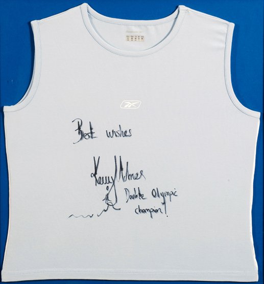 A Kelly Holmes signed running vest, by Reebok, pal: A Kelly Holmes signed running vest, by Reebok, pale blue, signed 'Best Wishes, Kelly Holmes, Double Olympic Champion', together with a hand drawn runner, mounted, framed & glazed, 72 by 67cm., 28 1/2