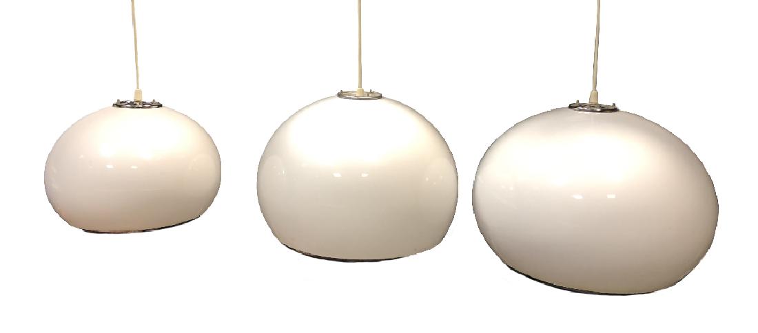 Attributed to Harvey Guzzini, a graduated set of three: Attributed to Harvey Guzzini, a graduated set of three white acrylic bulbous pendant lights, the largest 50cm (19.75in) diameter