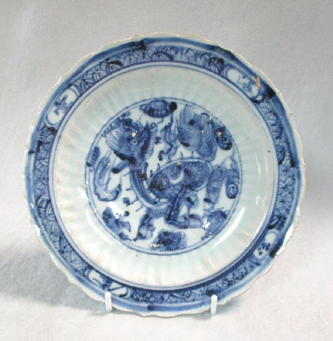 A 15th century Ming dynasty barbed dish,: A 15th century Ming dynasty barbed dish, painted with a Qilin roundel, the reverse cavetto moulding with incised flutes within a cloud-scroll band, 20.5cm diameter firing faults, chips and abrasion wa