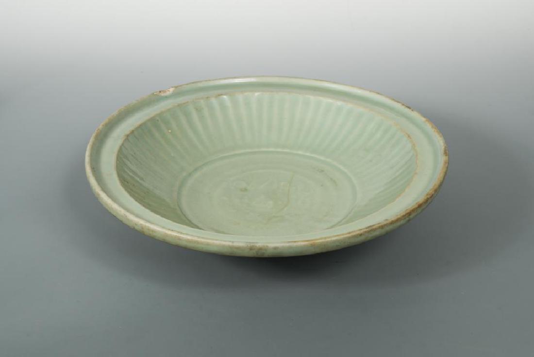 A Longquan celadon dish, Ming dynasty,: A Longquan celadon dish, Ming dynasty, the shallow rounded sides rising from a short tapering foot to a broad everted lipped rim, carved to the interior with a foliate medallion encircled by lobes in