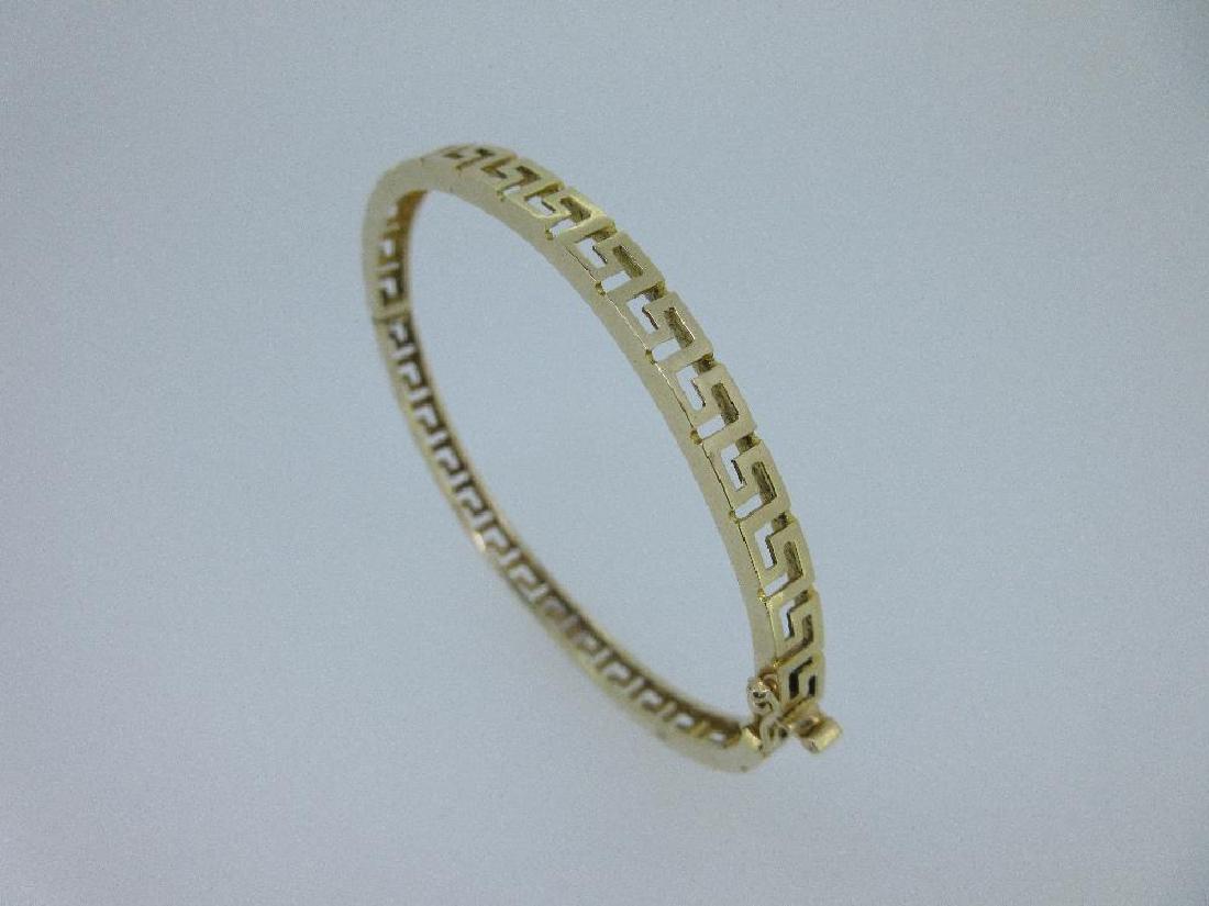 A Greek key pattern oval hinged bangle, (1 of 4)