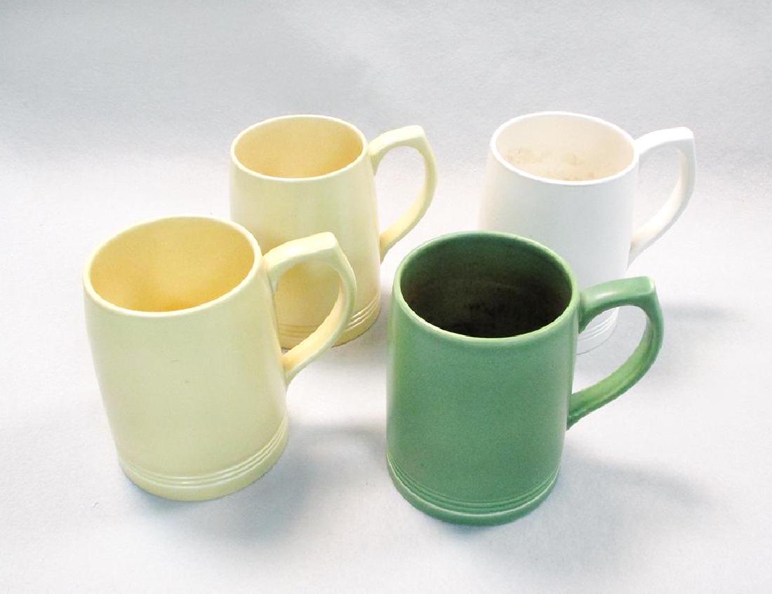 Keith Murray for Wedgwood, four cylindrical tankards,: Keith Murray for Wedgwood, four cylindrical tankards, each with banded design, two glazed in straw, one in moonstone and the other in green, printed marks (4) 12.50cm (5in)