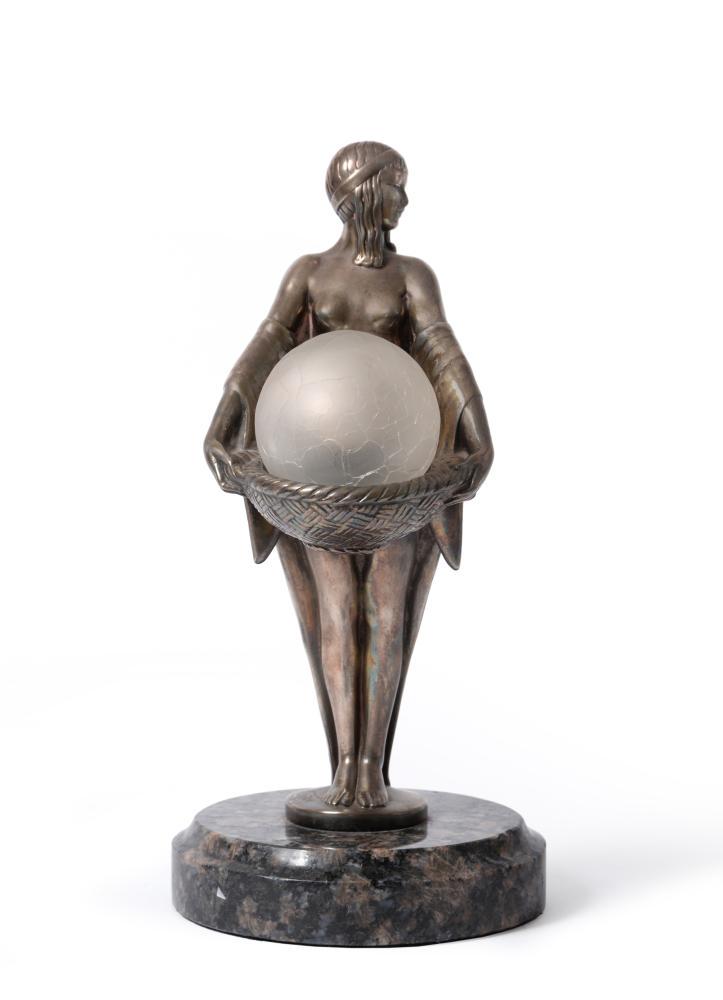 § Max Le Verrier (French, 1892-1973), an Art Deco: Â§ Max Le Verrier (French, 1892-1973), an Art Deco silvered metal figural table lamp, circa 1925, modelled as a half-nude classical maiden holding a crizzled glass sphere shade in a 'wicker' basket,