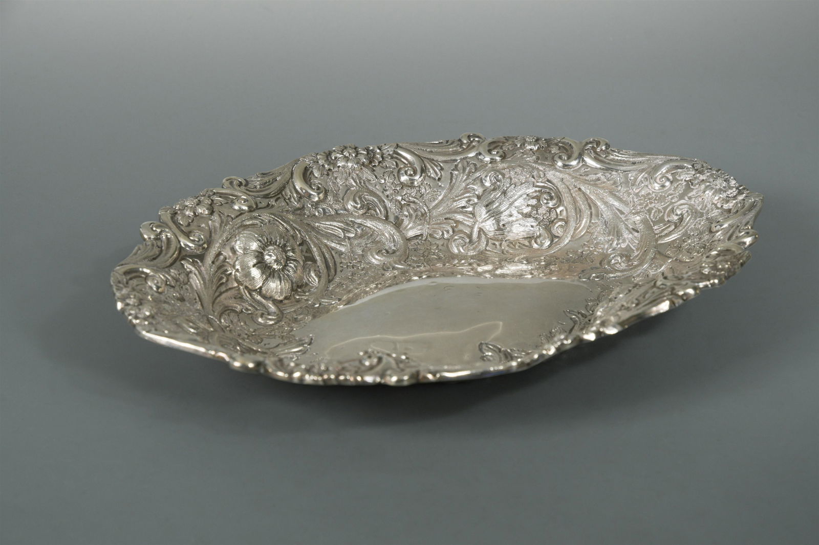 A Victorian silver fruit dish,: by Charles Stuart Harris, London 1890, of navette form, lavishly decorated with repoussÃ© scrolls and foliage around a central vacant slightly domed field, 15.5ozt (Dimensions: h: 4cm w: 30cm d: 23c