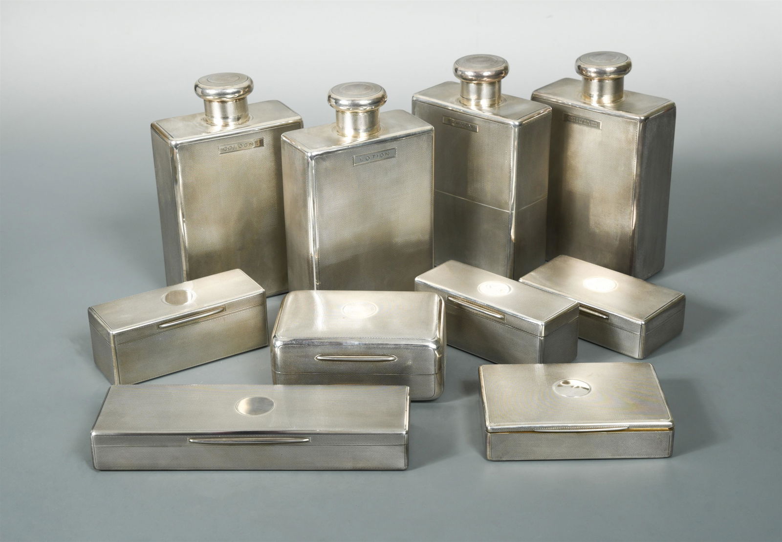 A George V silver 10 piece gentleman's toilet set,: by Wright & Davies (William Frederick Wright), London 1922, each decorated all over with engine turned engraving around a vacant circular cartouche, comprising four rectangular flasks each with screw