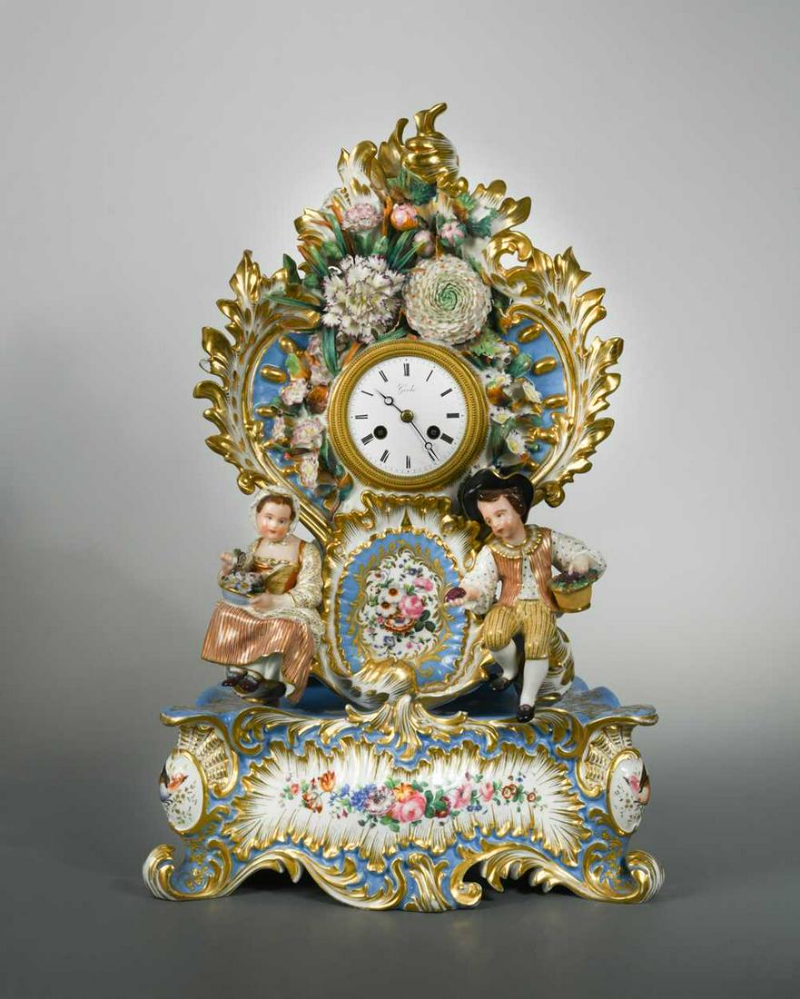 Jacob Petit, a turquoise cartouche shaped mantel clock: with a white enamelled dial with silk suspension movement, the case modelled with two figures in a floral arbour, 53cm high (including stand) (2)