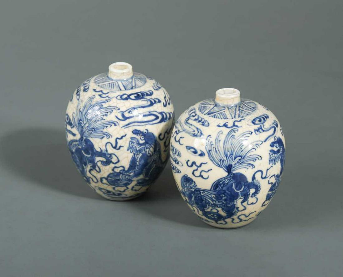 A pair of Chinese soft paste blue and white porcelain: each of ovoid shape painted with three playful foo dogs, each with six character mark of the Kangxi Emperor but later, 8cm high (2)