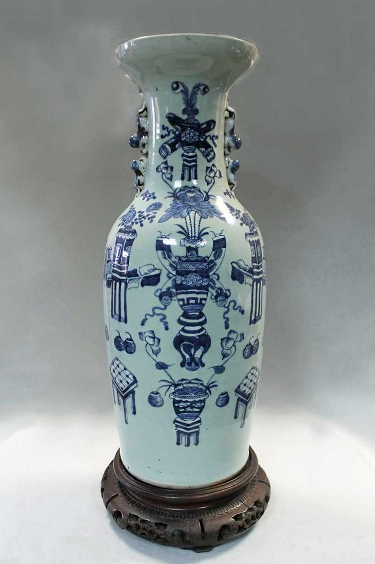 A Chinese celadon glazed large vase, circa 1900,: decorated in blue with precious objects, pairs of foo dogs to the shoulders, on associated wooden stand, 66cm high (2) Condition report: Good overall.