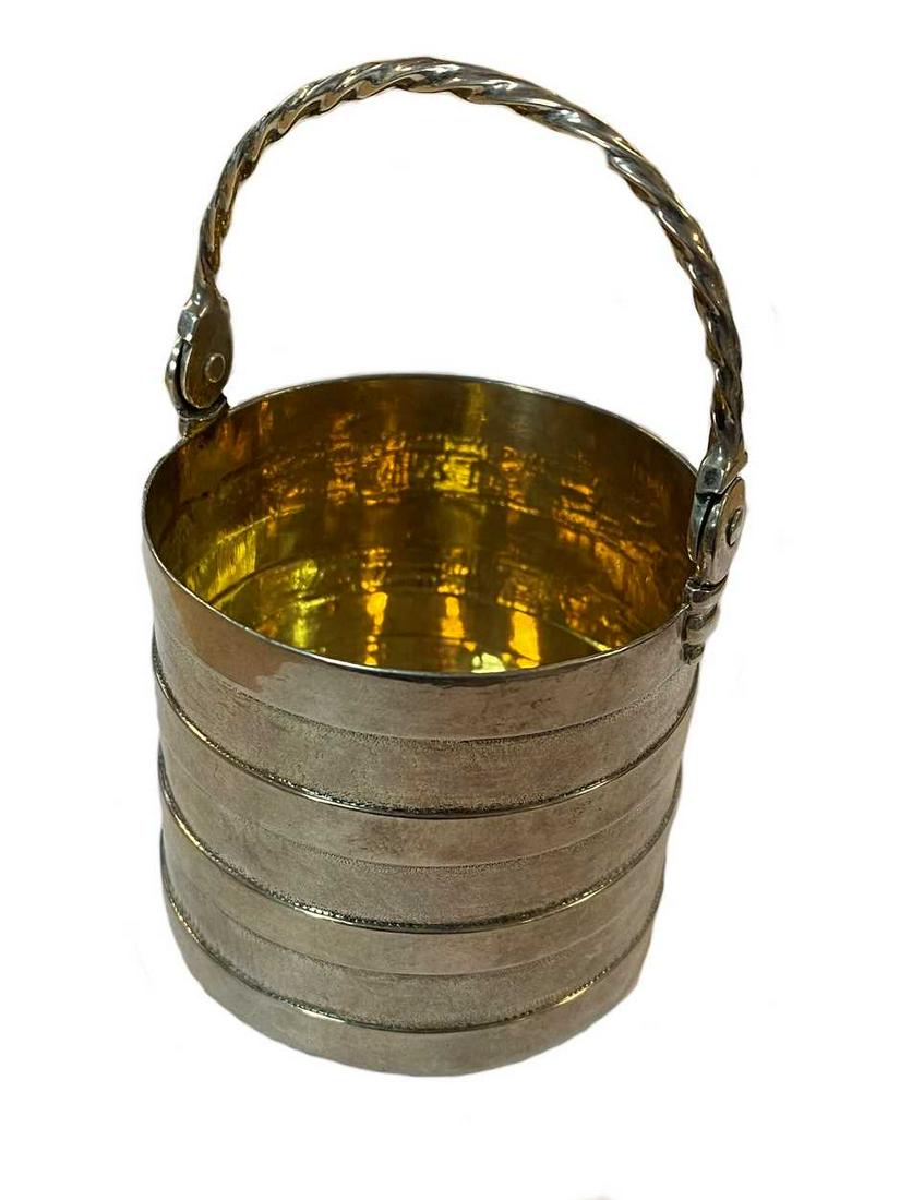 A George II silver novelty cream pail,: mark of Benjamin West, London 1751, in the form of a straight sided bucket with banded sides, gilded interior and hinged twisted wire handle, 6cm diameter, 9cm in height with the handle raised, 2.8ozt