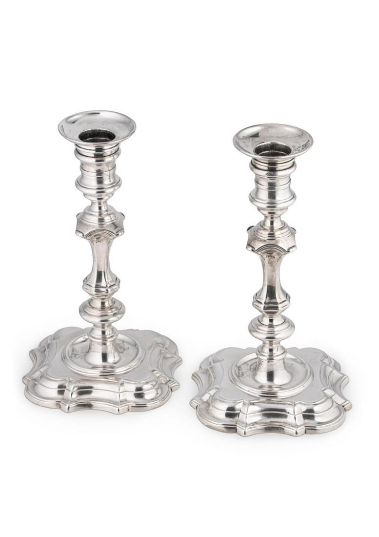 A pair of George II cast silver candlesticks, mark of George Wickes,: London 1744, each with quatrefoil scalloped edged base, knopped column, spool capital and part marked friction fitting removable wax pan, crested, 11.5 x 11.5cm, 20cm high, 33.2ozt gross (2)George Wic