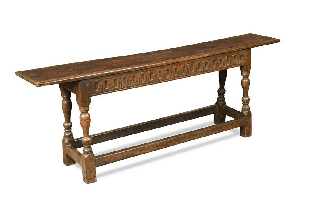 A carved oak bench, 17th century,: A carved oak bench, 17th century, the rectangular plank top with chip carved ends and moulded sides over a nulled-carved front frieze raised on turned baluster legs united by plain stretchers on block