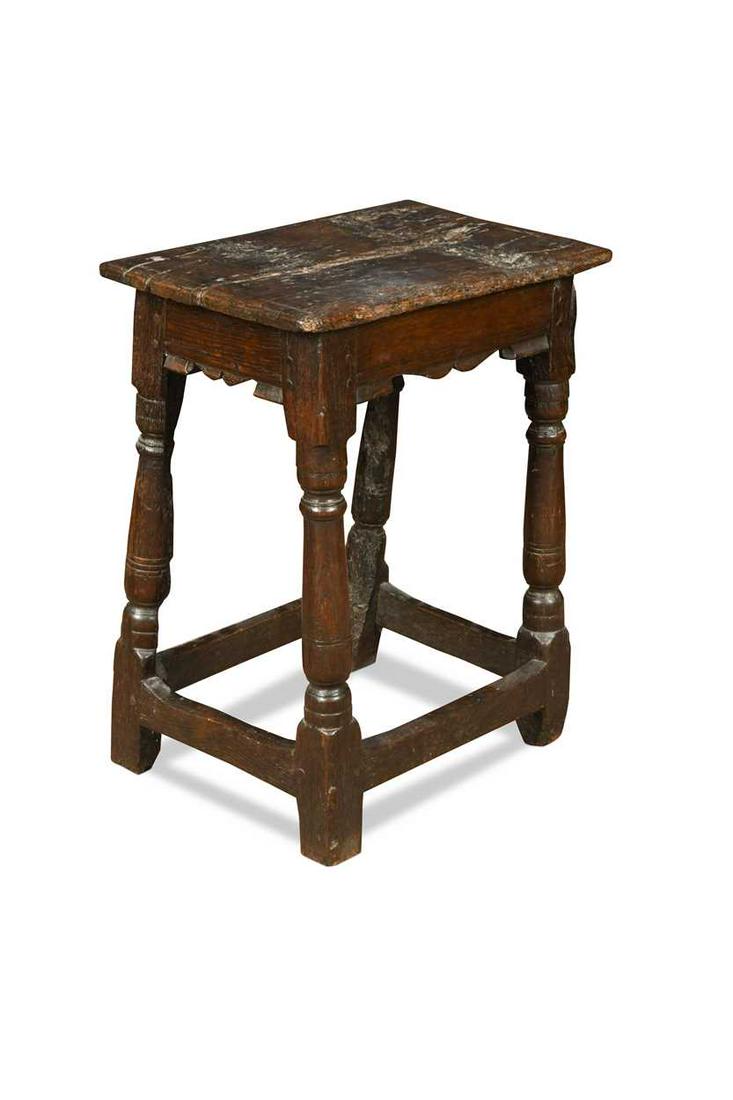 An oak joint stool, 17th century,: An oak joint stool, 17th century, the moulded top over a shaped bicuspid type frieze raised on turned legs and block feet united by stretchers 59 x 48 x 31cm Provenance: Property of a collector, remov